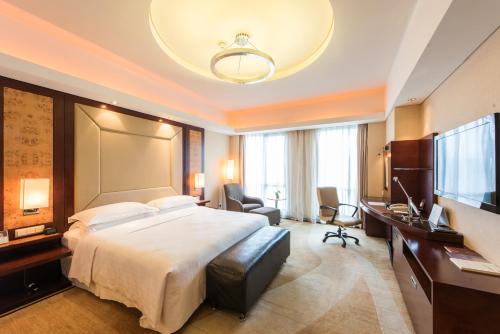 Habitación de hotel con cama grande y escritorio. en Sheraton Wenzhou Hotel en Wenzhou