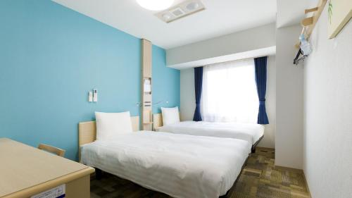 2 Betten in einem Zimmer mit blauen Wänden und einem Fenster in der Unterkunft Toyoko Inn Tokyo Keio-sen Higashi-fuchu-eki Kita-guchi in Fuchu