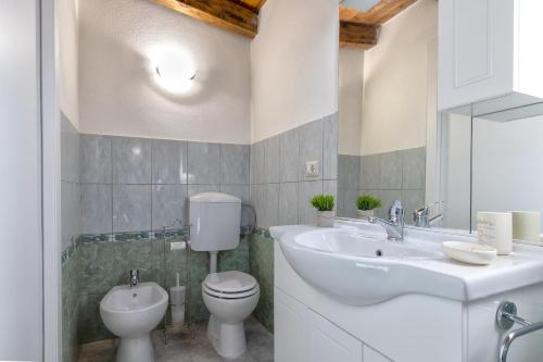 a white bathroom with a toilet and a sink at Isola di Giava Holiday in Sorso
