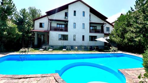 a house with a swimming pool in front of it at Tian-Shan Hotel in Bishkek