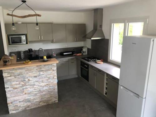 une cuisine avec un réfrigérateur blanc et un comptoir dans l'établissement Maison au cœur de la nature, à Saint-Nazaire-le-Désert