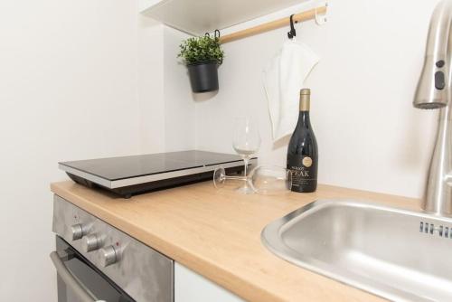 a kitchen counter with a sink and a bottle of wine at Cosy and Suits apartment in Jerusalem