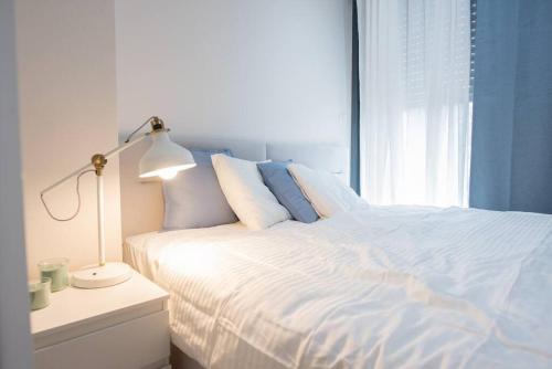1 dormitorio con 1 cama blanca con lámpara y ventana en Cosy and Suits apartment en Jerusalén