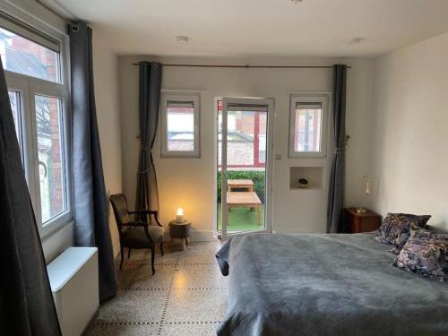 a bedroom with a bed and a chair and windows at Art Deco - Two bedroom apartment in Ghent