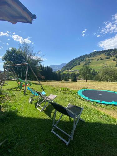 a swing and a chair in front of a pool at La Ferme des Georgières "Séjour en tout compris" in Notre-Dame-de-Bellecombe