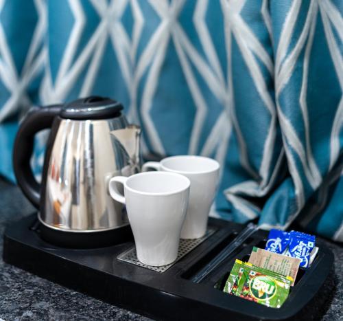 a tray with two cups and a tea kettle at Hotel Voila Atnest Suites Kokapet, Business Hotel in Hyderabad