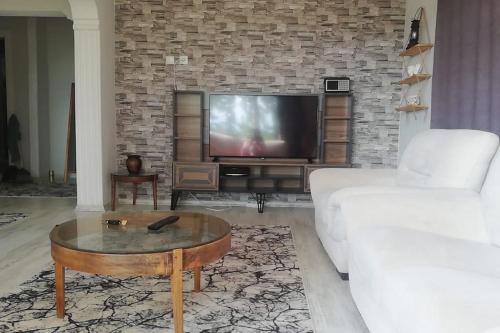 a living room with a white couch and a tv at göl manzarali ılıcaya ve göle 200m uzaklikta in Boyalıca