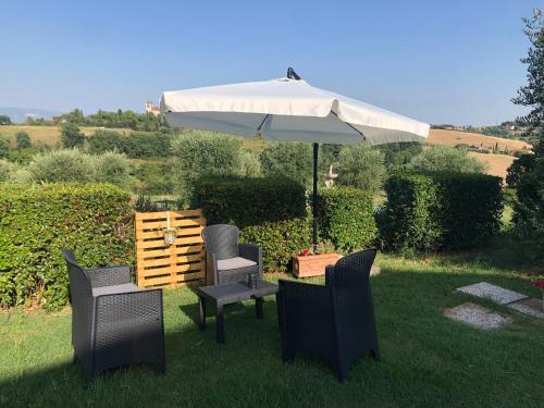 un patio con sombrilla, sillas y mesa en Casa vacanza da Lù, en Foiano della Chiana