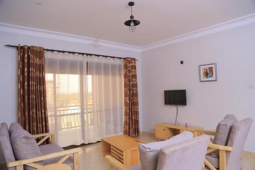 Una sala de estar con sillas, una mesa y un televisor. en The Junction Apartments, en Mbarara