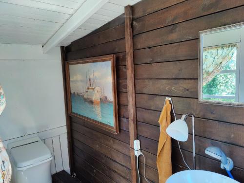 a bathroom with a wooden wall with a picture at Under Canvas Bornholm in Østermarie