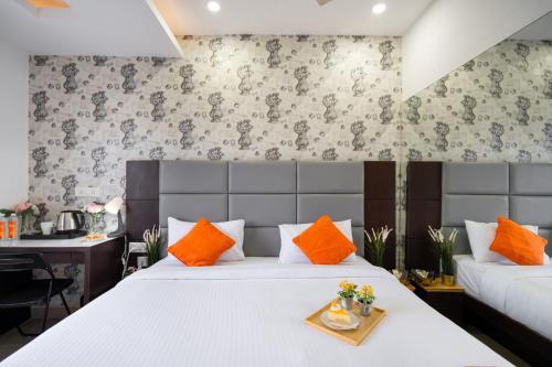 a bedroom with a bed with orange pillows and a desk at Hotel Marigold Atnest Gachibowli - A Business Hotel in Gachibowli
