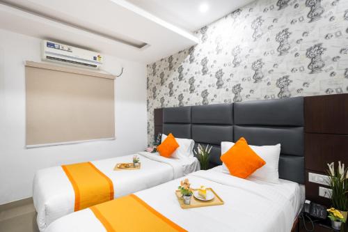 two beds in a room with orange and yellow pillows at Marigold At Nest in Gachibowli
