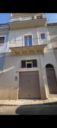 una casa bianca con un garage con un balcone di PONTEVECCHIO Accomodation a Ragusa