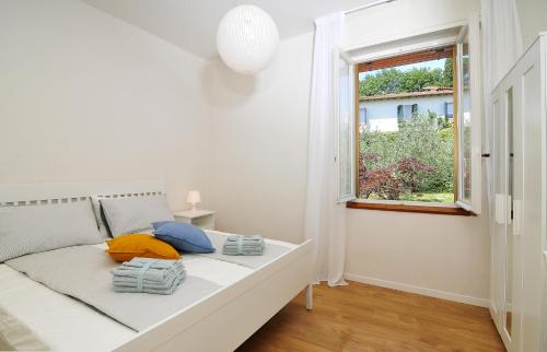 białe łóżko w pokoju z oknem w obiekcie Villa Cecilia w mieście San Felice del Benaco