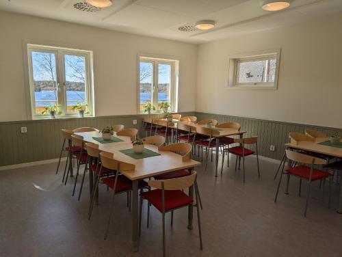 a dining room with tables and chairs and windows at Vårhaga Vandrarhem in Sjuntorp