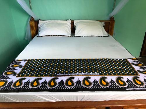 a bed with a black and yellow blanket on it at BeSwahilid B & B in Bagamoyo