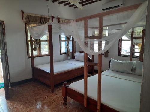 two bunk beds in a room with windows at Ames Nungwi in Nungwi