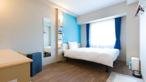 a small room with a bed and a mirror at Toyoko Inn Fujisan Otsuki-eki in Ōtsuki