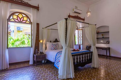 a bedroom with a canopy bed and a window at amã Stays & Trails Palmeira de Saligao, Goa in Old Goa