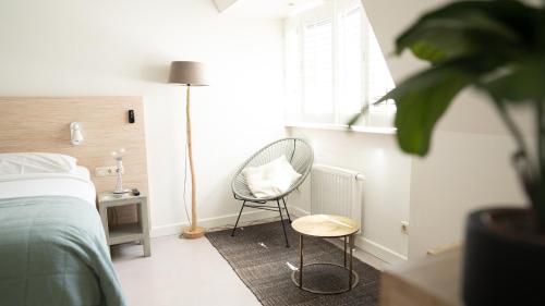 a bedroom with a chair and a bed and a window at Logement Overzee in Nes