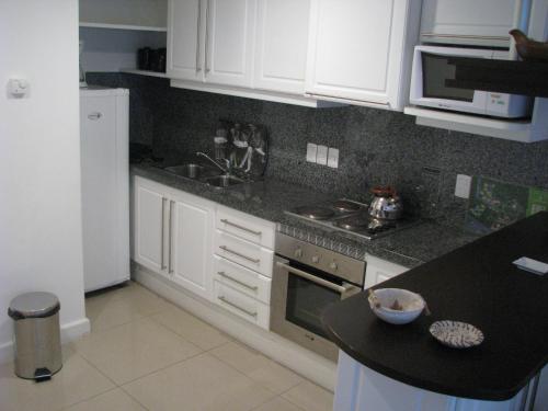 a kitchen with white cabinets and a black counter top at Green Park en Punta del Este in Punta del Este