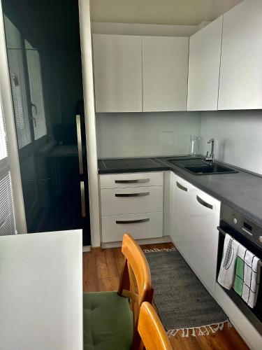 een keuken met witte kasten, een wastafel en een stoel bij 1 Bedroom Apartment w/Balcony in Rožňava