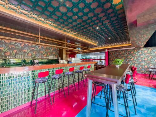 a bar with red chairs and a table in a restaurant at Ramada by Wyndham Bangkok Ten Ekamai Residences in Bangkok