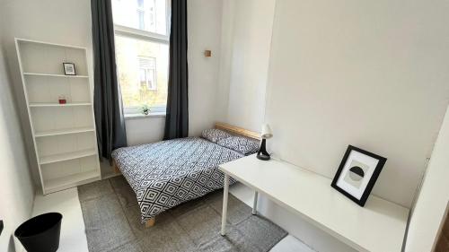 um quarto com uma secretária, uma cama e uma janela em Nice bedroom near the bus and train station na Cracóvia