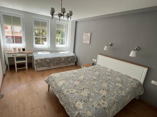 1 dormitorio con 2 camas, escritorio y 2 ventanas en Good morning Ohrid, en Ohrid