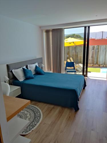 1 dormitorio con cama azul y ventana grande en Hibiscus Afife, en Afife