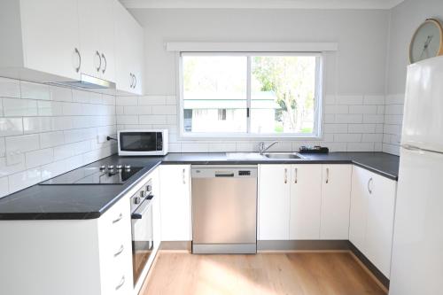 a white kitchen with white cabinets and a window at Glen Villa Resort in Byron Bay