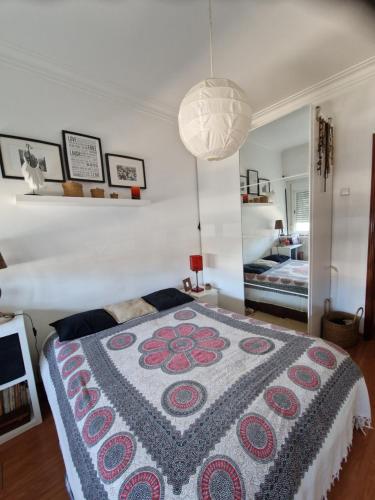 um quarto com uma cama com um cobertor colorido em Casa da catarina em Linda-a-Velha