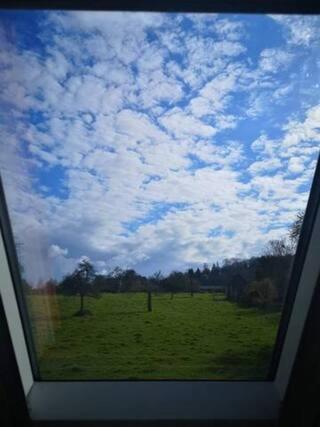 a window view of a field with a cloudy sky at Les Lys in Cricquebœuf