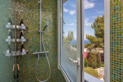 a shower with a glass door next to a window at Villa Verde Costa Brava - BY EMERALD STAY in Begur
