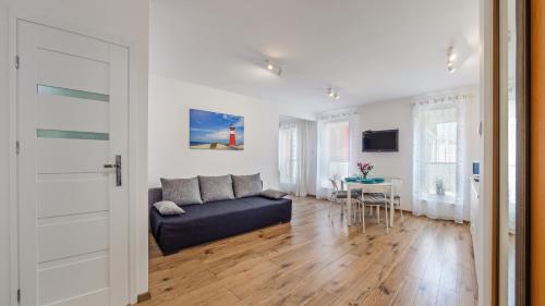 a living room with a blue couch and a table at Apartamenty Sun & Snow Latarnia in Władysławowo