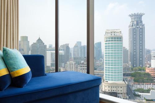 una silla azul en una habitación con vistas a la ciudad en Renaissance Shanghai Yu Garden Hotel en Shanghái