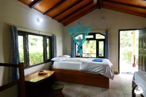 a bedroom with a bed in a room with windows at Bardia Homestay Pvt. Ltd. in Bhurkīā