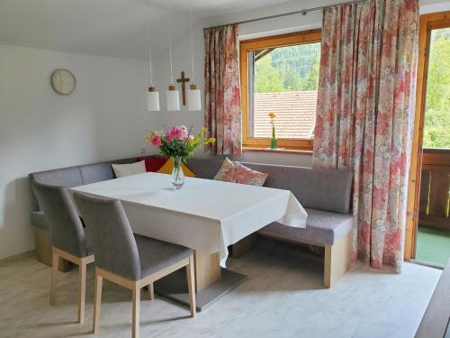 d'une salle à manger avec une table, des chaises et une fenêtre. dans l'établissement Haus an der Sonne FeWo 2, à Biberwier