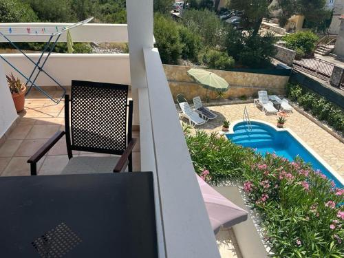 a balcony with a pool and chairs and an umbrella at Villa West Point in Okrug Donji