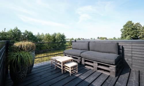 a couch and a table on a wooden deck at GreenFloat Boskoop #2 Mica & Luca in Boskoop