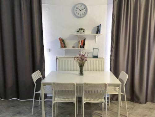 a white dining room table with chairs and a clock on the wall at Polynikis Apartment in Nikiti