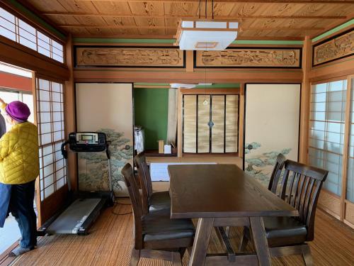 eine Person steht in einem Zimmer mit einem Tisch und Stühlen in der Unterkunft 余呉の里山-ランプの宿-さくら in Nagahama