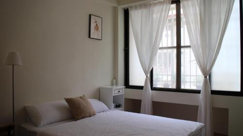 1 dormitorio con 1 cama y 2 ventanas grandes en 棲息所 Habitat Inn, en Yuanlin