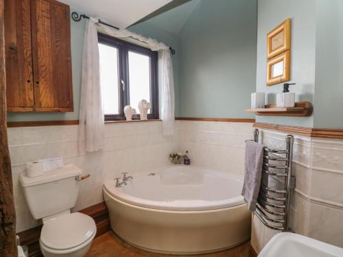 a bathroom with a tub and a toilet and a sink at The Haybarn in Lichfield