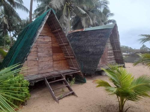 een kleine hut op een strand met palmbomen bij Tiliponan Nipa Hut in Buenavista