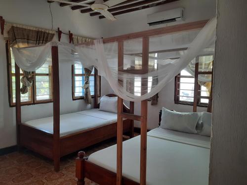 two bunk beds in a room with windows at AMESbungalows in Nungwi