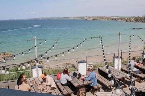 a group of people sitting at picnic tables near the beach at St Christopher's Inn Newquay in Newquay