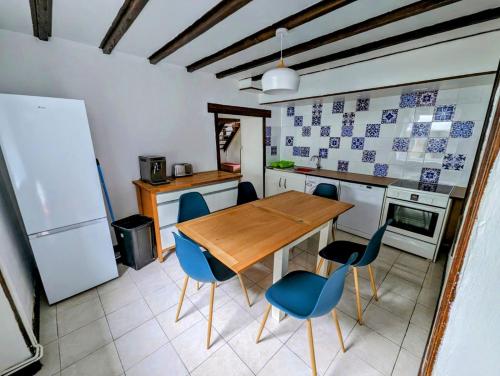 une cuisine avec une table en bois et des chaises bleues dans l'établissement Les Gites de la Cabache, à Montaigu-les-Bois