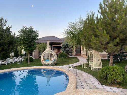 una piscina con due sedie a dondolo accanto a una casa di Zima-Leto a G‘azalkent