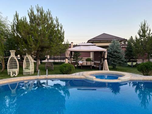 a swimming pool with chairs and a gazebo at Zima-Leto in G‘azalkent
